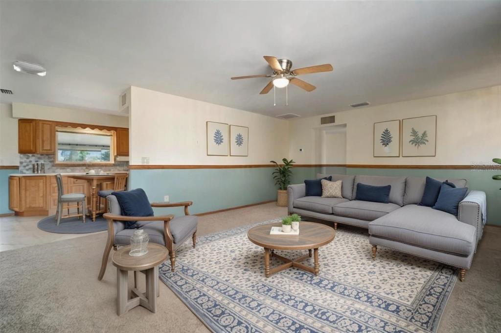 A living room with a sectional sofa, armchair, and an adjacent kitchen area — 609 FOX HILLS DRIVE, SUN CITY CENTER, FL