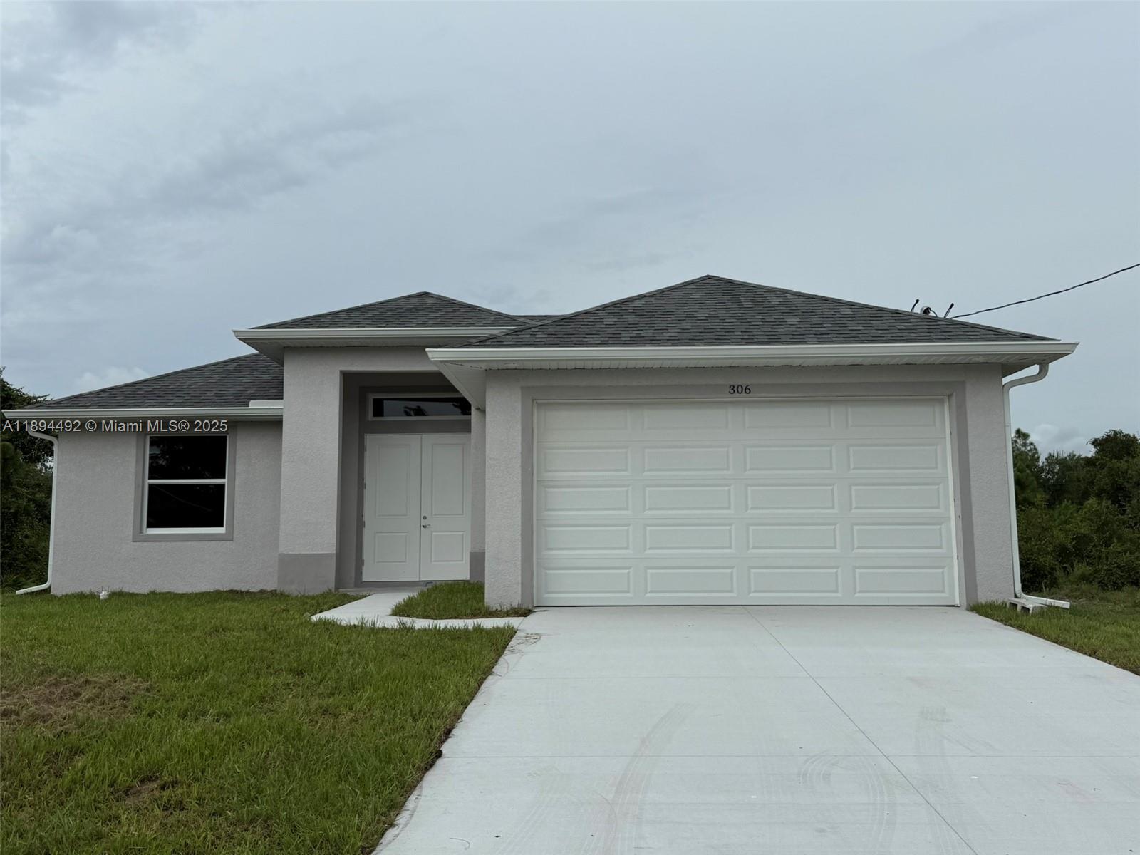 A single-story house with a gray stucco exterior, a white double door, and a garage — 306 Lenz Ave S, Lehigh Acres FL 33974, LEHIGH ACRES, FL