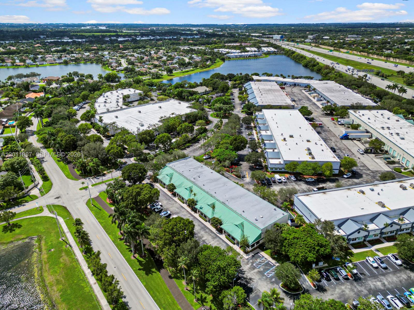 An aerial view shows several commercial warehouse buildings with green and white roofs near a highway — 735 Shotgun Rd, Sunrise FL 33326, SUNRISE, FL
