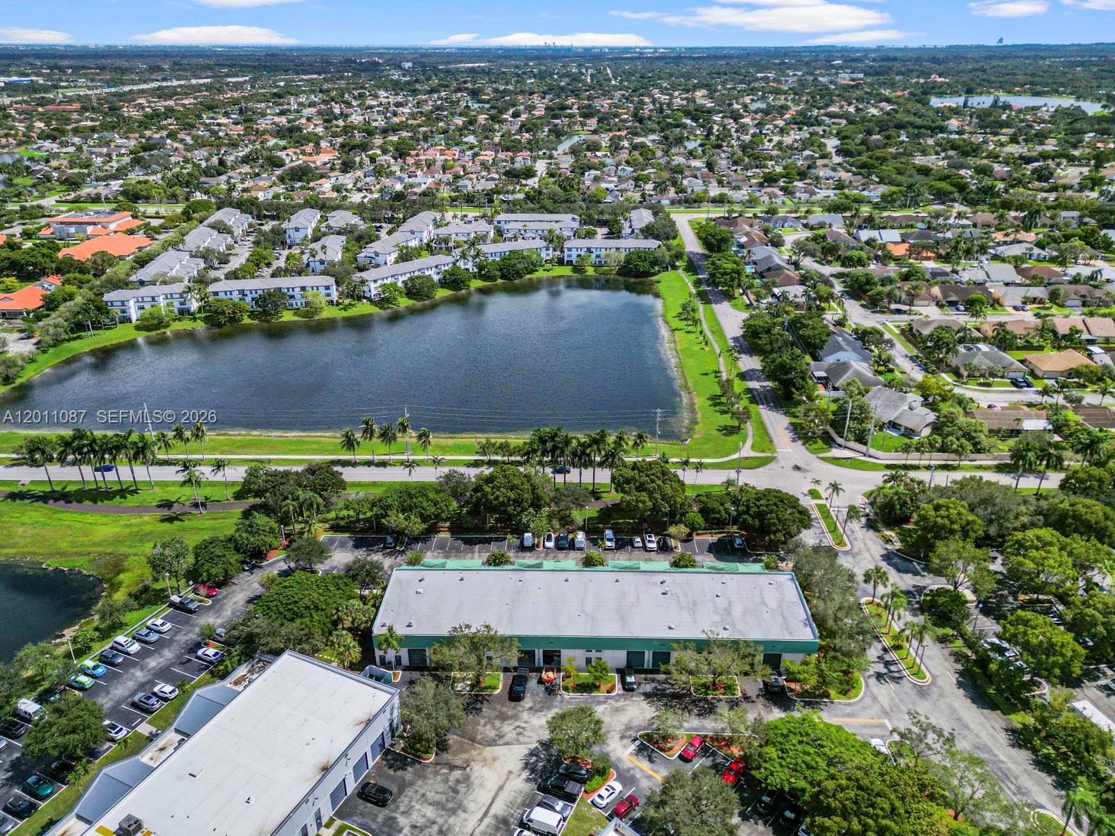 An aerial view shows a commercial building with a parking lot next to a lake — 735 Shotgun Rd, Sunrise FL 33326, SUNRISE, FL