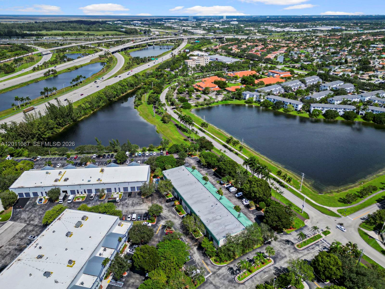 An aerial view shows industrial buildings, parking lots, and a large lake near a highway — 735 Shotgun Rd, Sunrise FL 33326, SUNRISE, FL