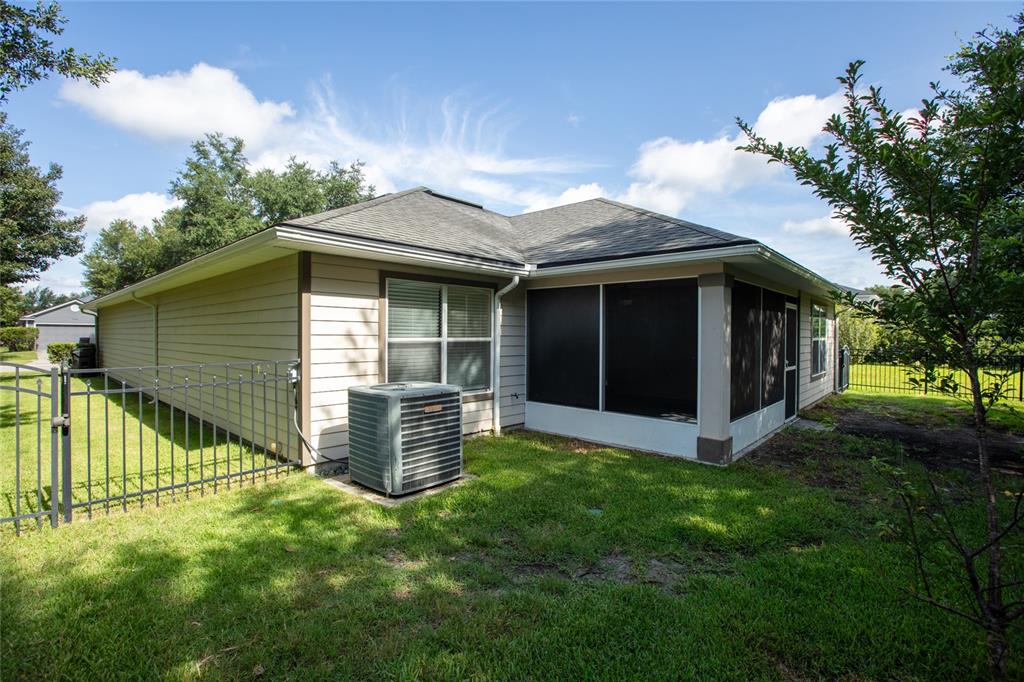 The exterior view shows a house with beige siding, a screened-in porch, and an AC unit — 8123 NW 51ST DRIVE, GAINESVILLE, FL