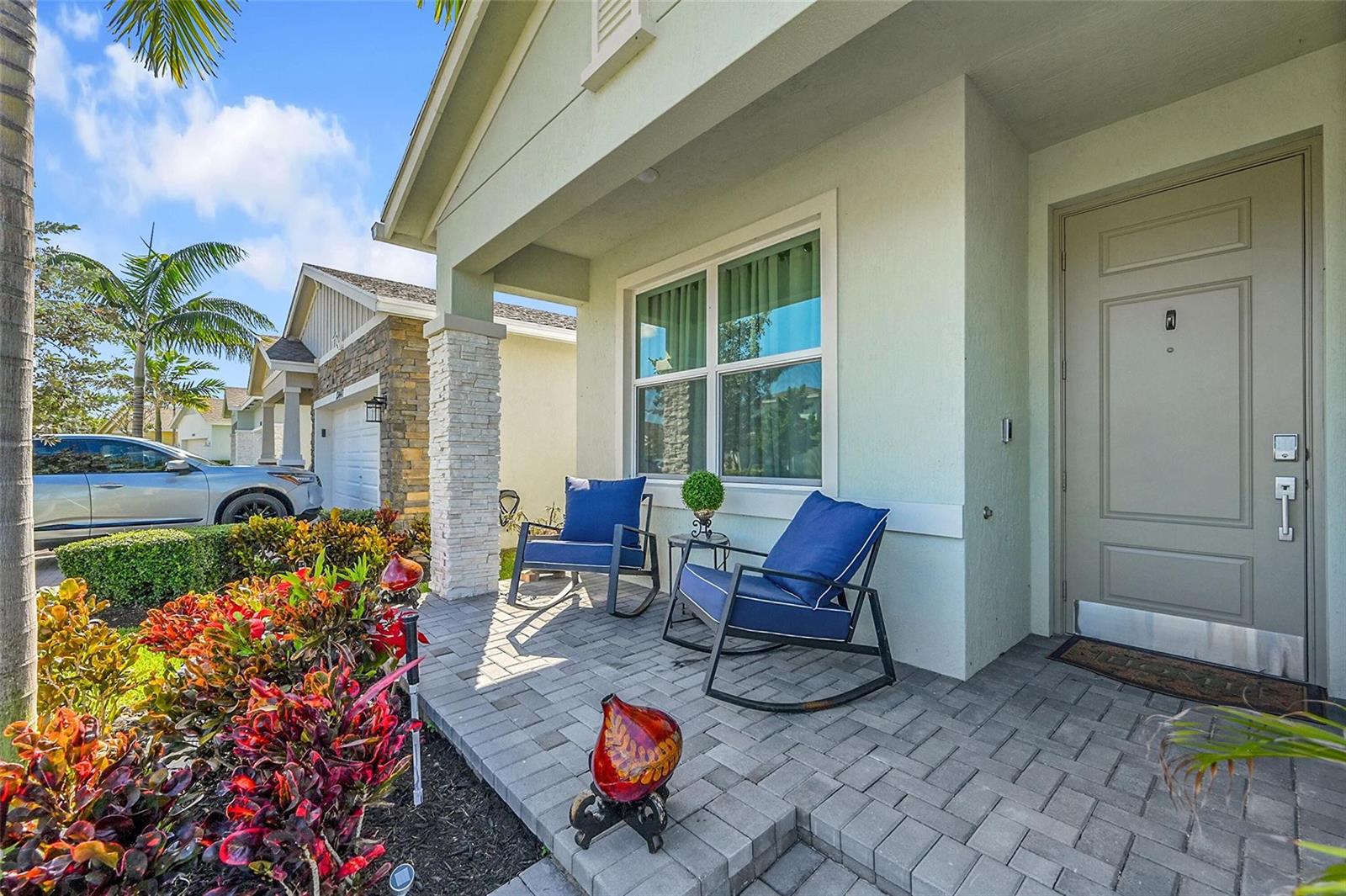 A front porch features two blue rocking chairs, a small table, and stone pavers — 13443 Noble Drive, Delray Beach FL 33484, DELRAY BEACH, FL