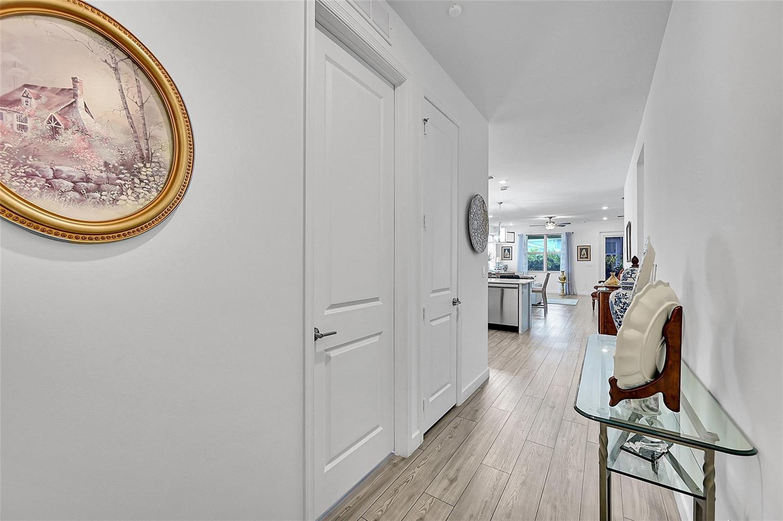 A hallway with light wood flooring leads to an open-concept kitchen and living area — 13443 Noble Drive, Delray Beach FL 33484, DELRAY BEACH, FL