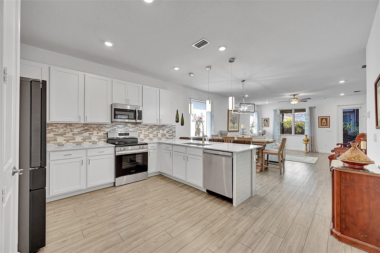A modern kitchen with white cabinets, stainless steel appliances, and an island with a sink — 13443 Noble Drive, Delray Beach FL 33484, DELRAY BEACH, FL