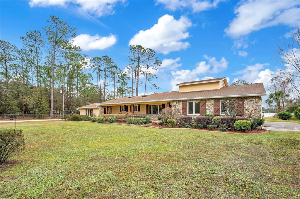 A single-story house with a stone facade and yellow siding sits on a grassy lawn — 11450 FANGORN ROAD, ORLANDO, FL