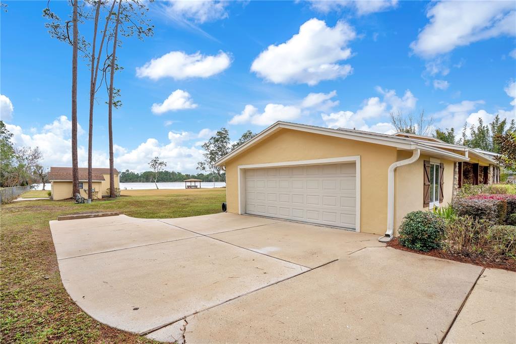 A yellow house with a two-car garage sits on a lawn near a lake — 11450 FANGORN ROAD, ORLANDO, FL