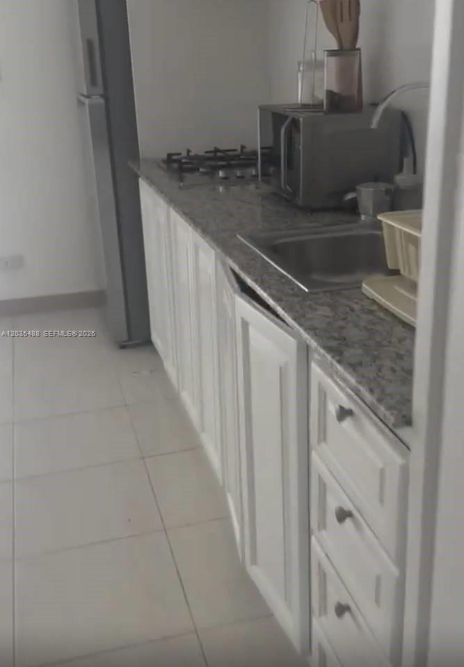 This kitchen features white cabinets, a granite countertop, a stainless steel sink, and a stovetop — 23000 ciudad las canas # 0, FL