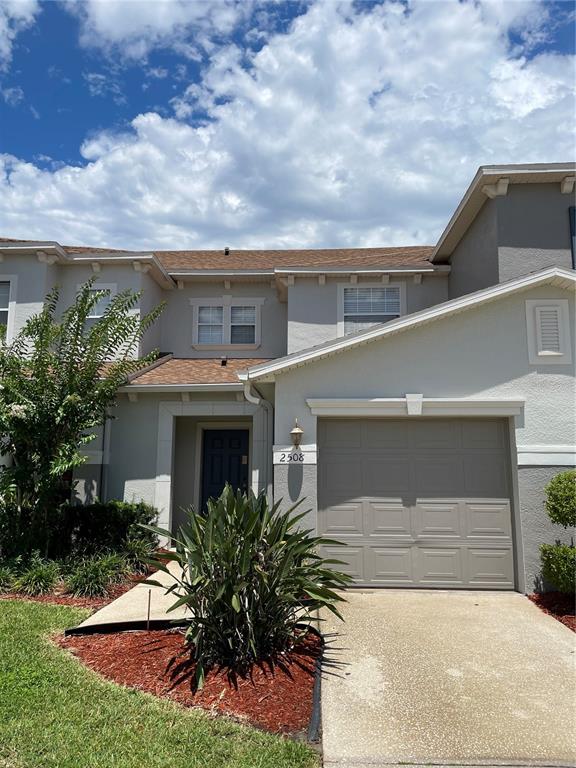 A two-story residential building features a beige stucco exterior, a garage, and a front entrance — 2508 HASSONITE STREET, KISSIMMEE, FL