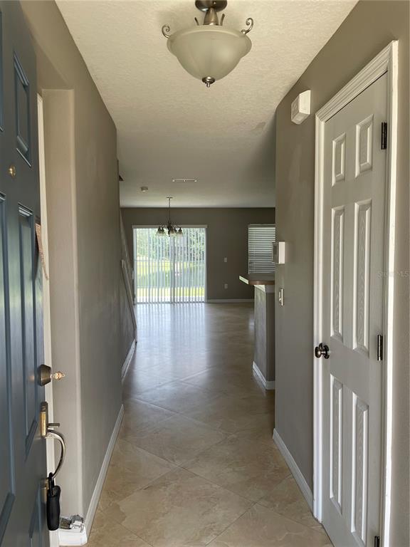 An entryway with tile flooring leads into an open living area with a sliding glass door — 2508 HASSONITE STREET, KISSIMMEE, FL