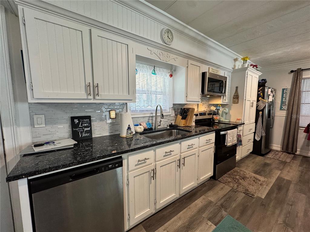 A kitchen features white cabinets, dark granite countertops, stainless steel appliances, and a tiled backsplash — 420 49TH STREET E UNIT 45, PALMETTO, FL