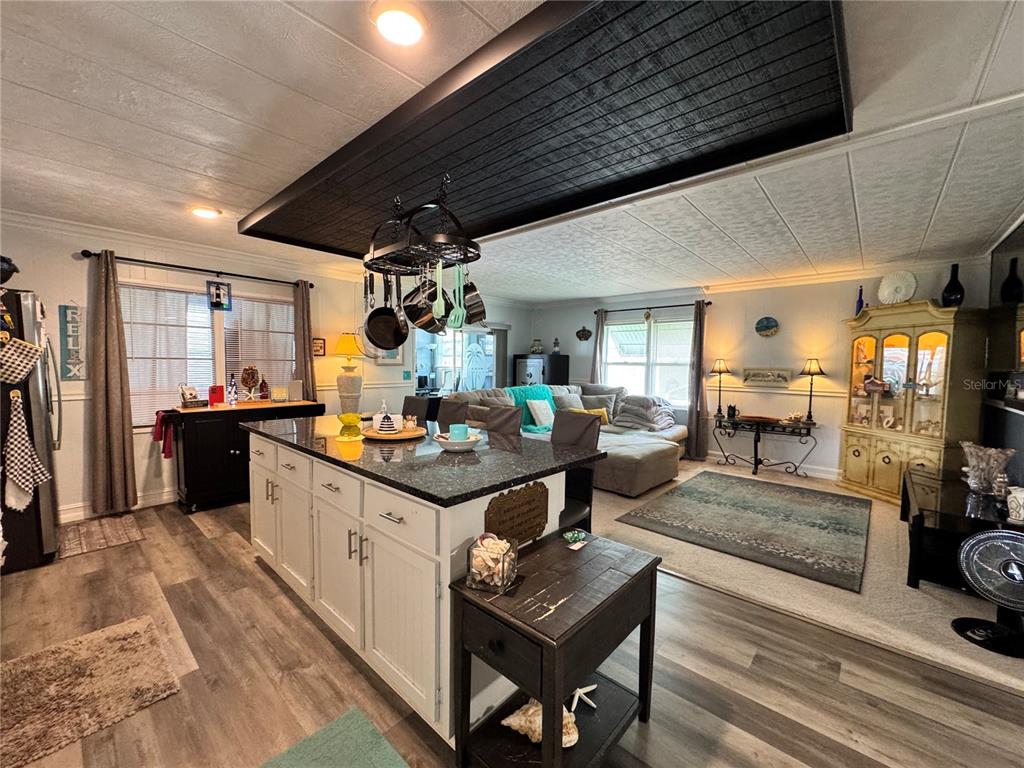 An open-concept kitchen and living area featuring a large island, dark wood ceiling accent, and flooring — 420 49TH STREET E UNIT 45, PALMETTO, FL