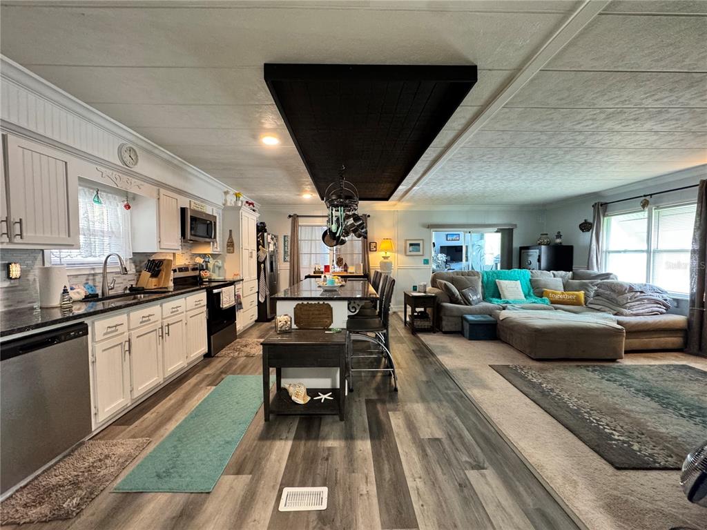 An open-concept kitchen and living area featuring white cabinets, a central island, and wood-look flooring — 420 49TH STREET E UNIT 45, PALMETTO, FL