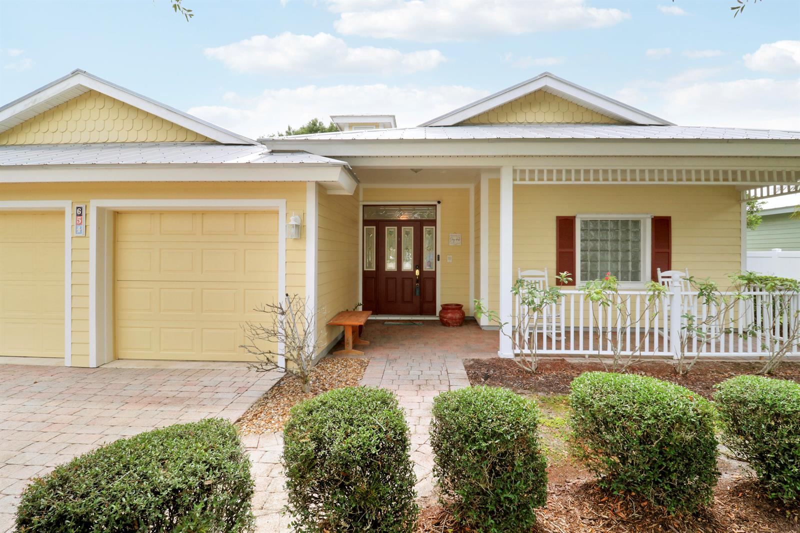 A yellow house with a white porch, brick walkway, and a two-car garage — 654 NE Little Kayak Point, FL 34983, FL