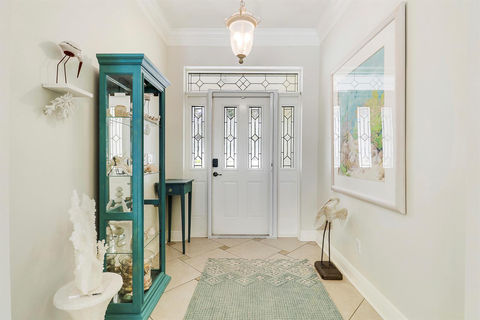 A bright entryway features a teal display cabinet, a patterned rug, and a glass-paneled door — 654 NE Little Kayak Point, FL 34983, FL