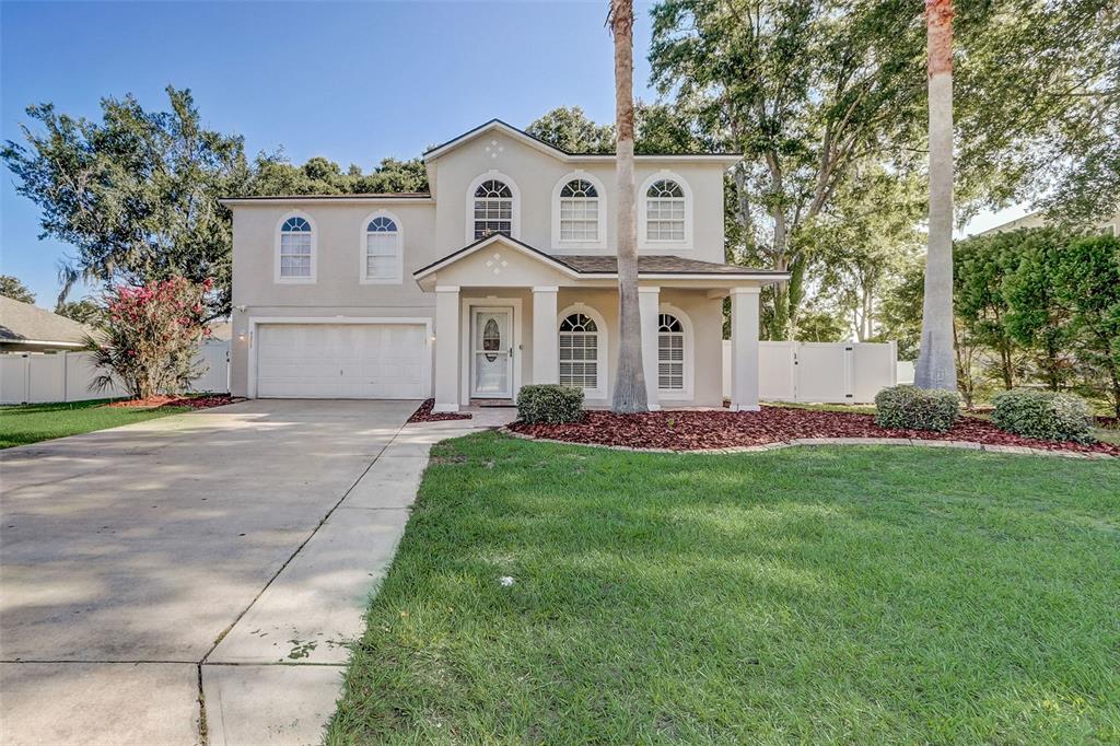 A two-story beige house with a two-car garage, arched windows, and a front porch — 4215 SW 32ND STREET, OCALA, FL