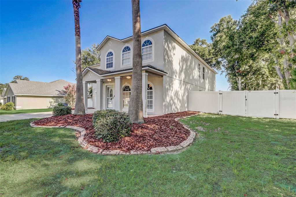 A two-story house with a beige exterior, arched windows, and a white vinyl privacy fence — 4215 SW 32ND STREET, OCALA, FL