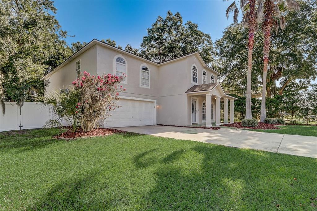 A two-story beige house with a two-car garage, arched windows, and a columned front porch — 4215 SW 32ND STREET, OCALA, FL
