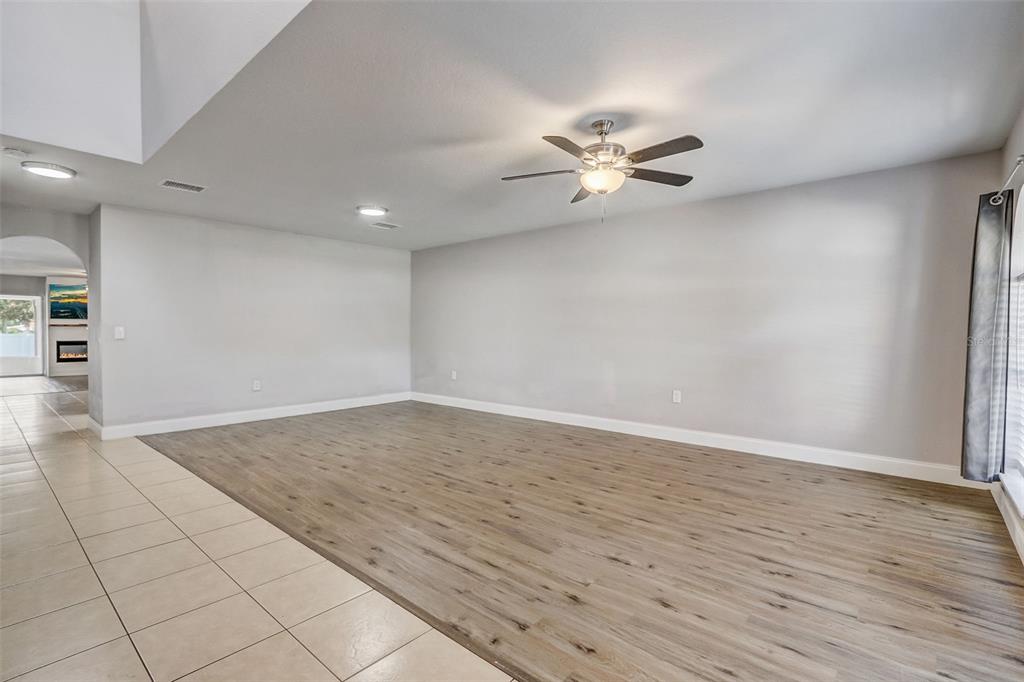 A spacious living area features light-colored walls, wood-look flooring, and a ceiling fan — 4215 SW 32ND STREET, OCALA, FL