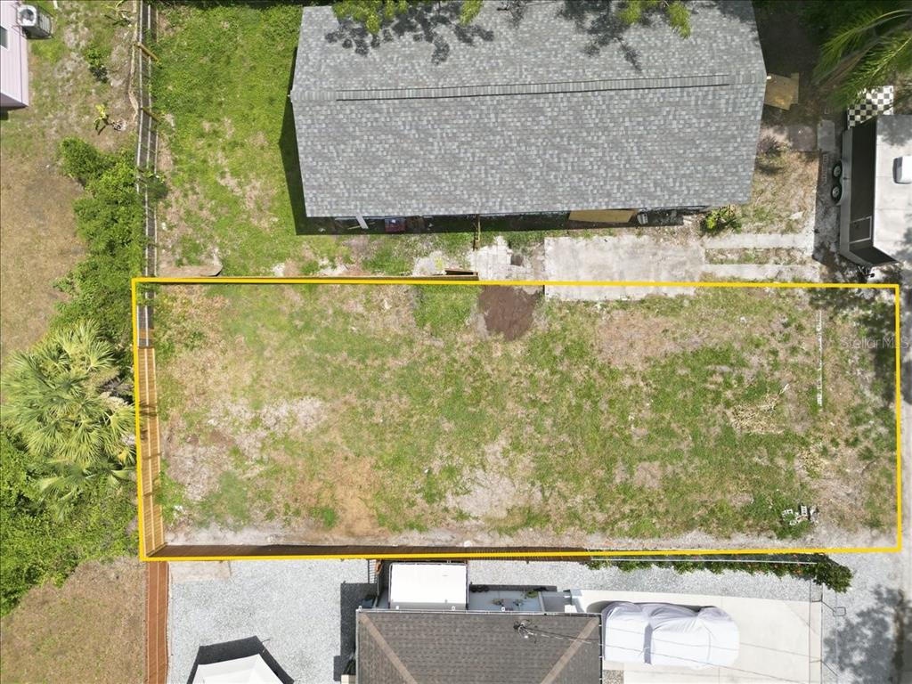 An aerial view shows a rectangular, fenced-in vacant lot situated between two residential properties — 3107 N 24TH STREET, TAMPA, FL