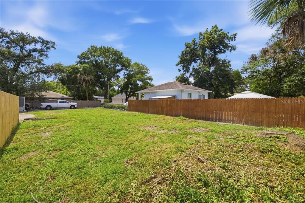 A vacant, grassy residential lot is enclosed by wooden privacy fences under a blue sky — 3107 N 24TH STREET, TAMPA, FL