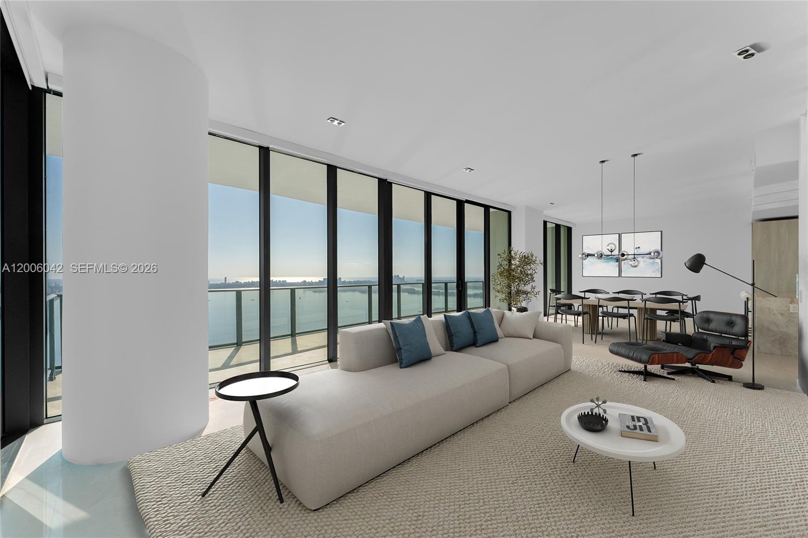 A modern living room features a large sofa, lounge chair, and floor-to-ceiling windows overlooking water — 3131 NE 7th Ave, Miami FL 33137, MIAMI, FL