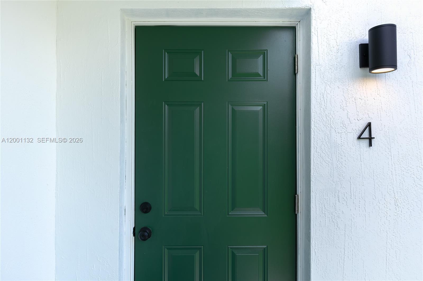 A green six-panel front door with black hardware is set in a white stucco wall — 6125 SW 40th Ct # 4, Miramar FL 33023, MIRAMAR, FL