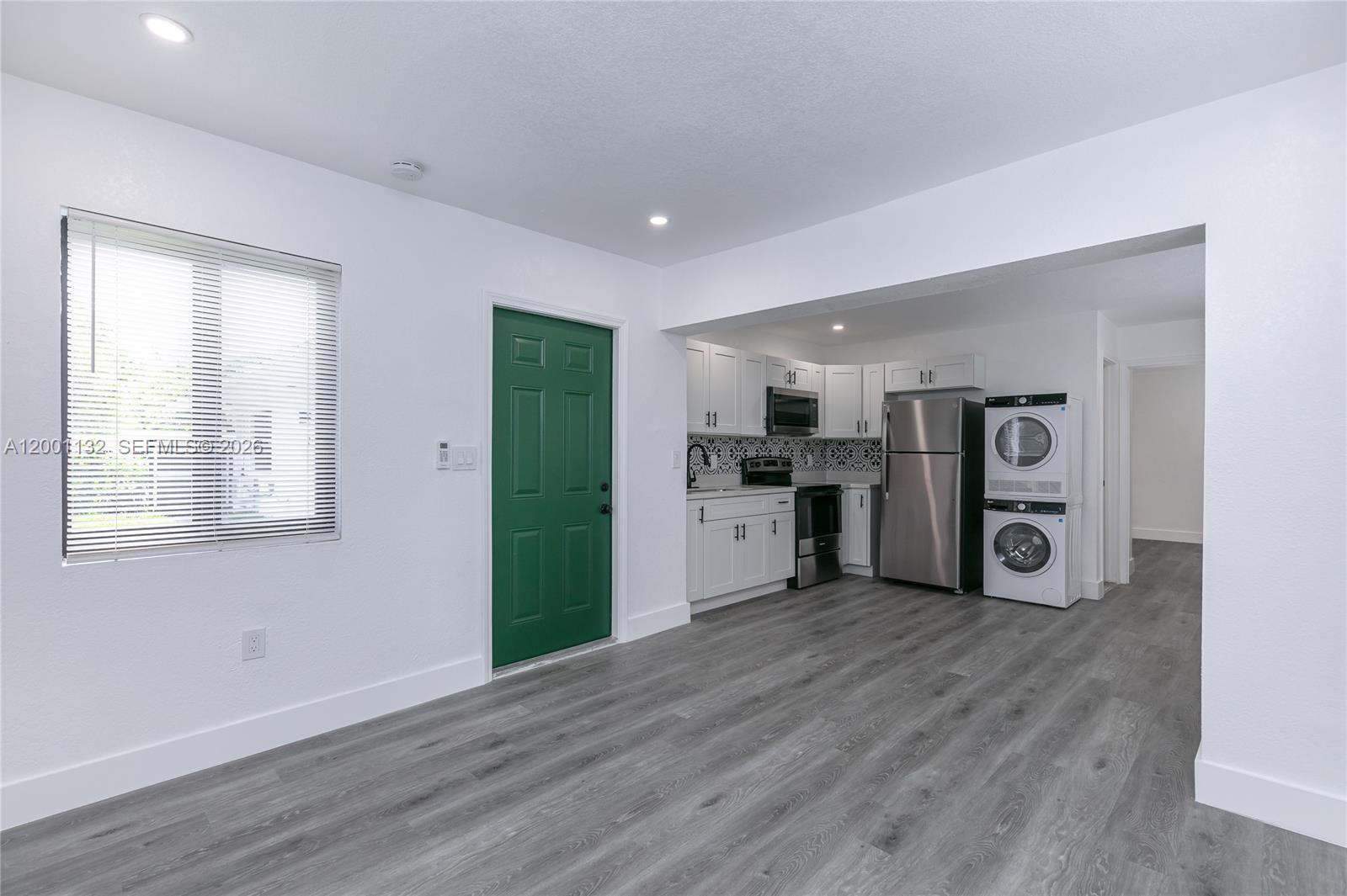 A studio apartment features a kitchen with white cabinets, stainless appliances, and a stacked washer-dryer — 6125 SW 40th Ct # 4, Miramar FL 33023, MIRAMAR, FL