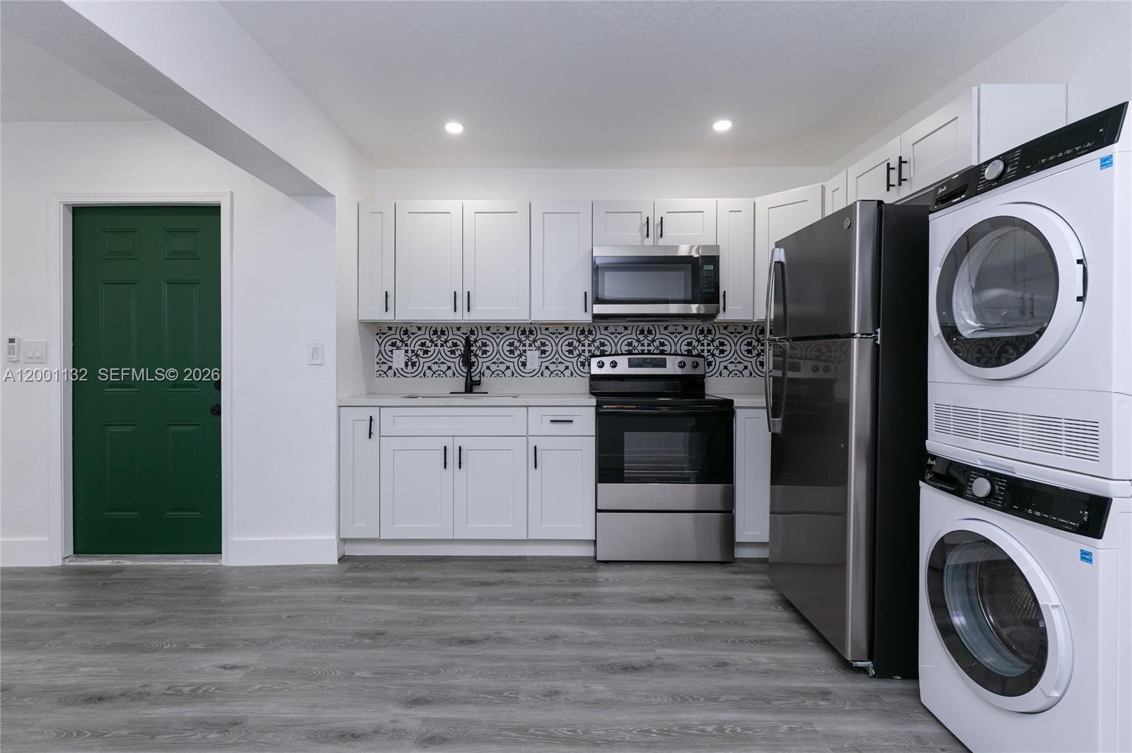 A kitchen features white cabinets, stainless steel appliances, a patterned backsplash, and a green door — 6125 SW 40th Ct # 4, Miramar FL 33023, MIRAMAR, FL