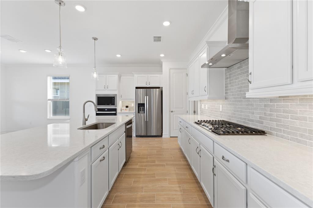 A modern kitchen features white cabinetry, stainless steel appliances, a large island, and tile flooring — 4559 NW 53RD AVENUE ROAD, OCALA, FL