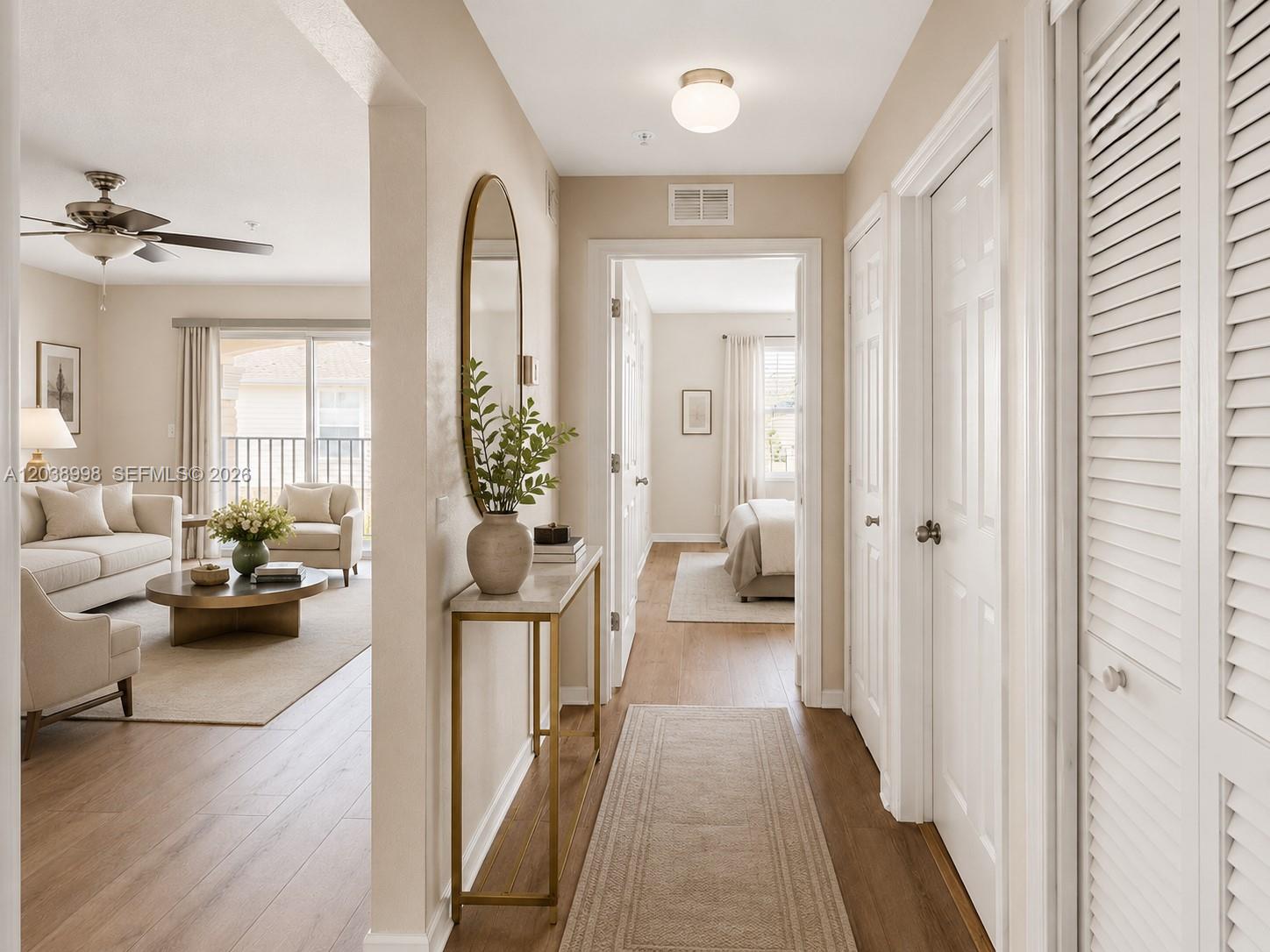 A hallway with a console table and mirror leads to a living room and bedroom — 4026 MEANDER PL # 208, Rockledge FL 32955, ROCKLEDGE, FL
