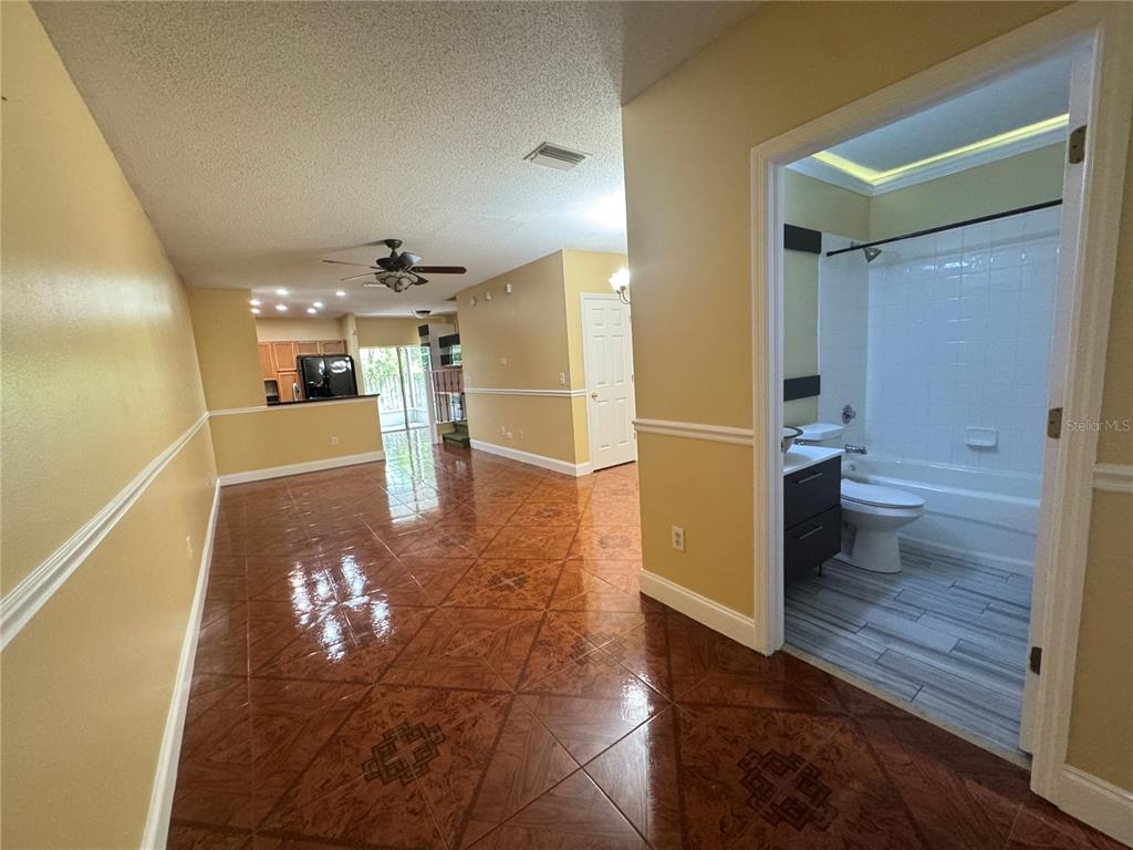 A view of a tiled living area leading to a kitchen and a full bathroom — 6229 OSPREY LAKE CIRCLE, RIVERVIEW, FL