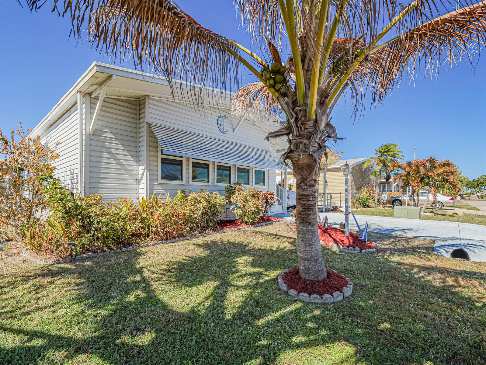 A light-colored mobile home features a palm tree in the front yard under a clear sky — 7566 Montauk Avenue # U19, FL 32976, FL