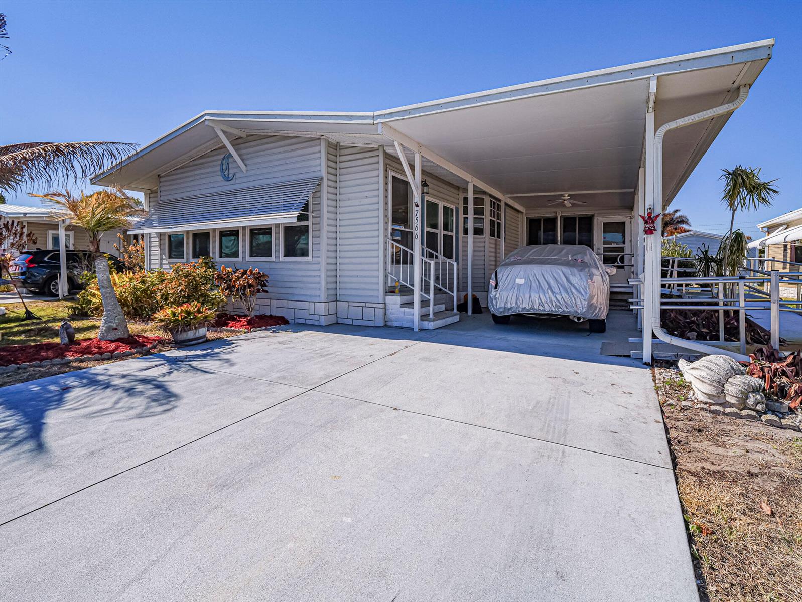 A single-story manufactured home with a carport, concrete driveway, and a covered front entrance — 7566 Montauk Avenue # U19, FL 32976, FL