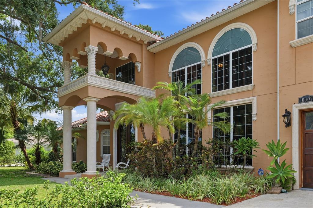 The exterior of a two-story stucco house features a covered balcony with decorative columns — 10307 RECLINATA LANE, TAMPA, FL