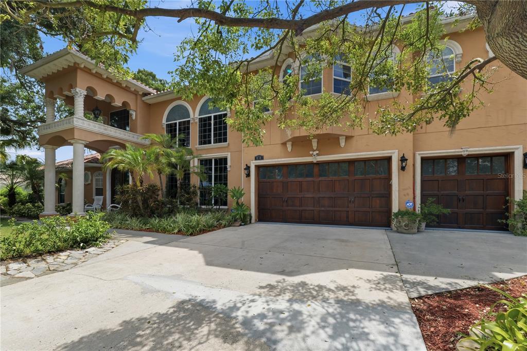 A two-story stucco house features a three-car garage and a covered second-story balcony — 10307 RECLINATA LANE, TAMPA, FL