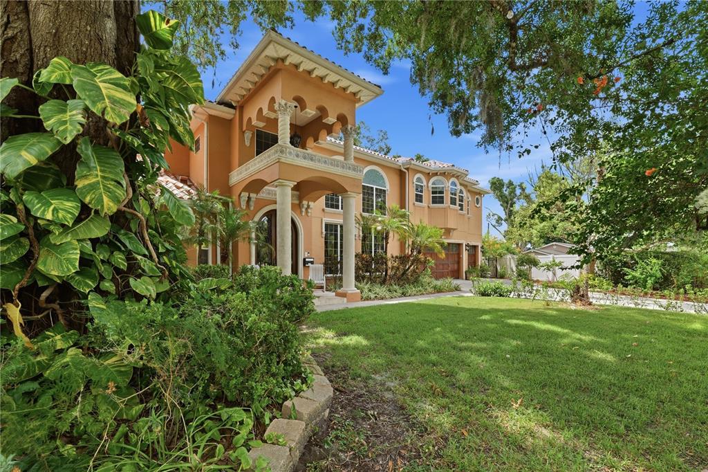 A two-story Mediterranean-style house with a stucco exterior, arched balcony, and a landscaped front yard — 10307 RECLINATA LANE, TAMPA, FL