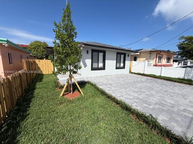 A white house with a paved driveway and a wooden fence on a sunny day — 644 NW 6th Ct, Hallandale Beach FL 33009, HALLANDALE BEACH, FL