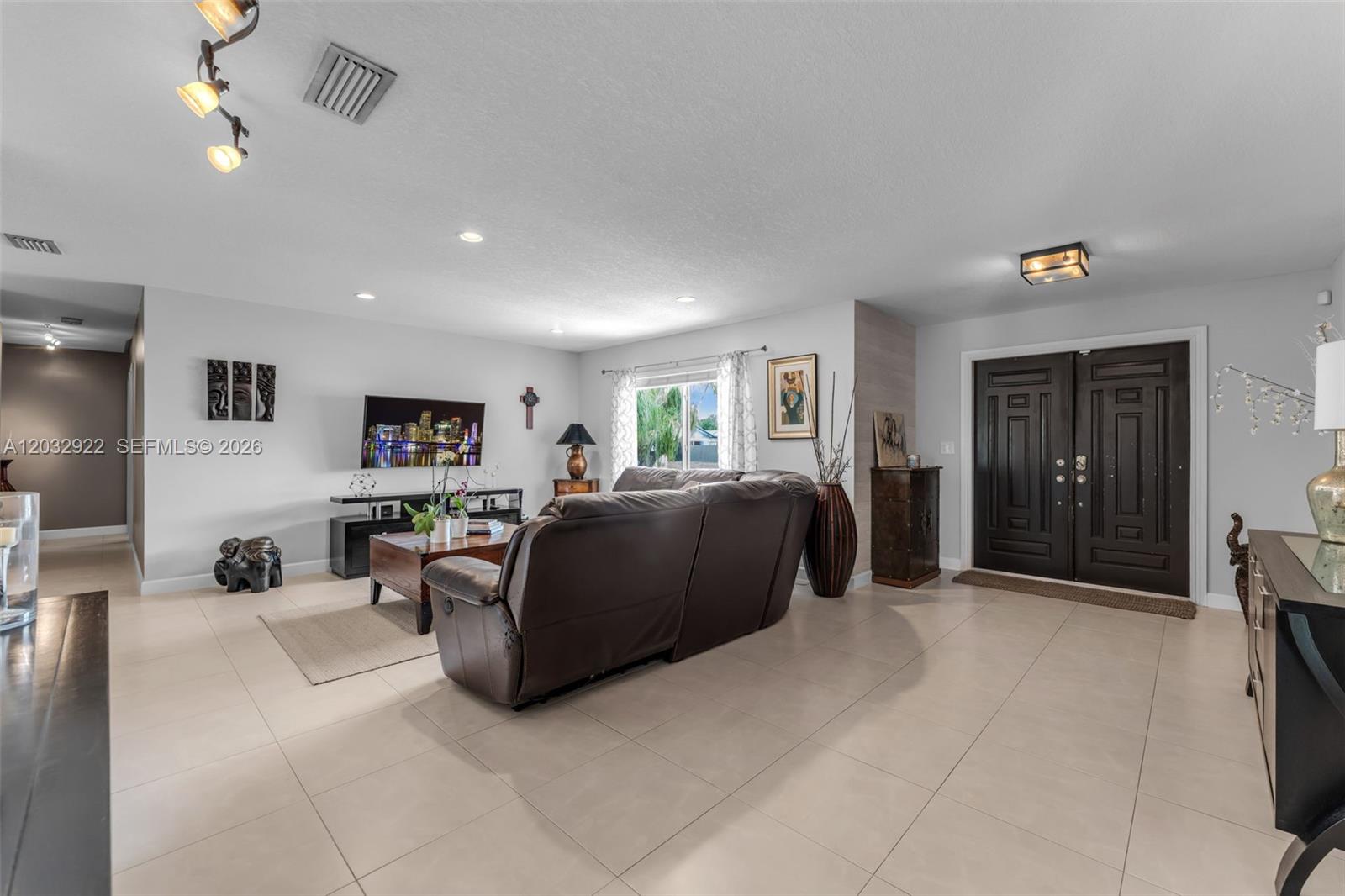 A living room features light tile floors, a dark leather sofa, and double entry doors — 14061 SW 39th St, Miami FL 33175, MIAMI, FL
