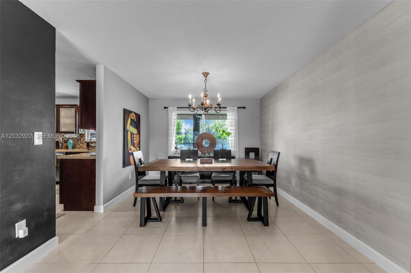 A dining room features a wooden table with a bench, chairs, and a chandelier — 14061 SW 39th St, Miami FL 33175, MIAMI, FL