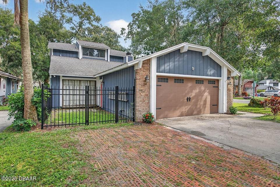 A two-story house features blue vertical siding, a brick facade, and a brown garage door — 28 BAYMEADOW COURT, ORMOND BEACH, FL