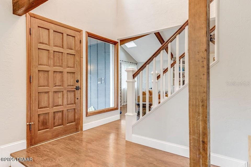 A foyer features a wooden front door, hardwood flooring, and a staircase with white railings — 28 BAYMEADOW COURT, ORMOND BEACH, FL