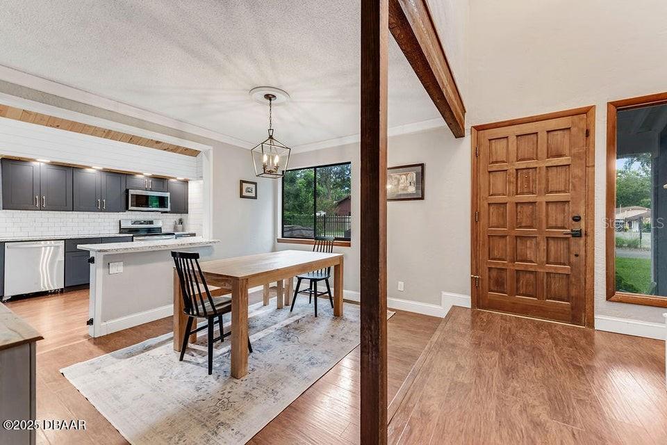 A dining area with a wooden table sits adjacent to a kitchen with dark cabinets — 28 BAYMEADOW COURT, ORMOND BEACH, FL