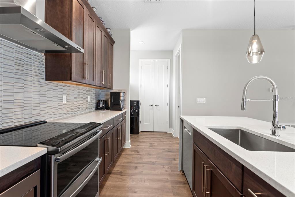 A kitchen features dark wood cabinets, white countertops, stainless steel appliances, and a tile backsplash — 2521 11TH PLACE N, ST PETERSBURG, FL