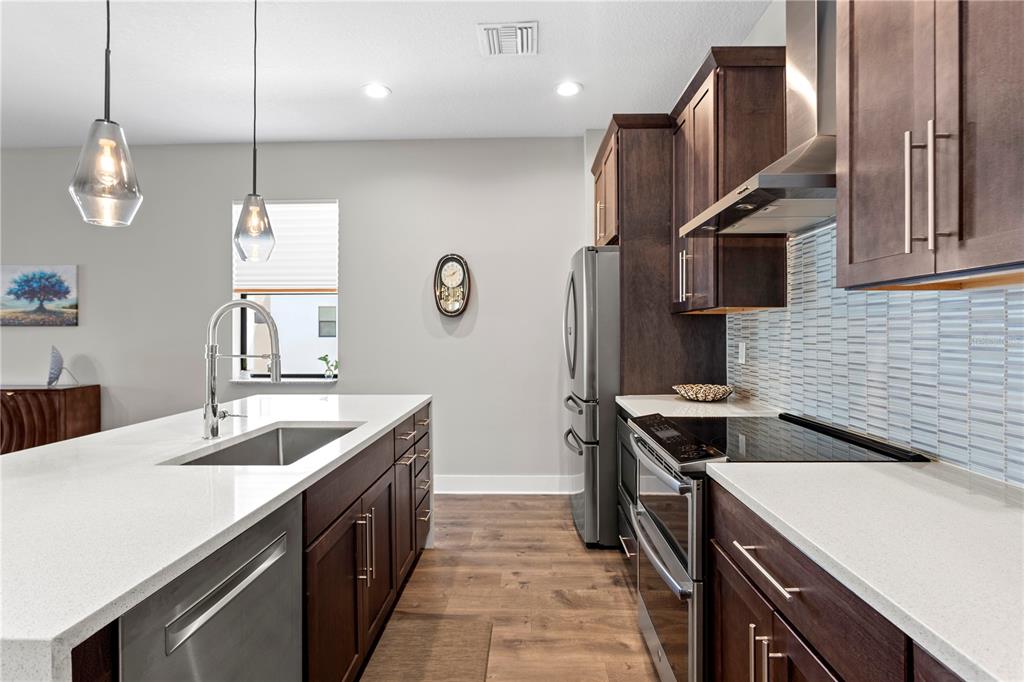A modern kitchen features dark wood cabinets, white countertops, stainless steel appliances, and pendant lighting — 2521 11TH PLACE N, ST PETERSBURG, FL