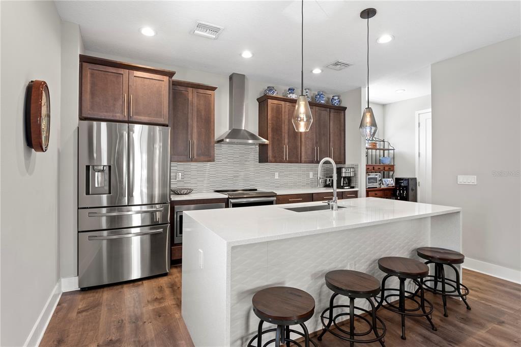 A modern kitchen features dark wood cabinets, stainless steel appliances, and a white quartz island — 2521 11TH PLACE N, ST PETERSBURG, FL