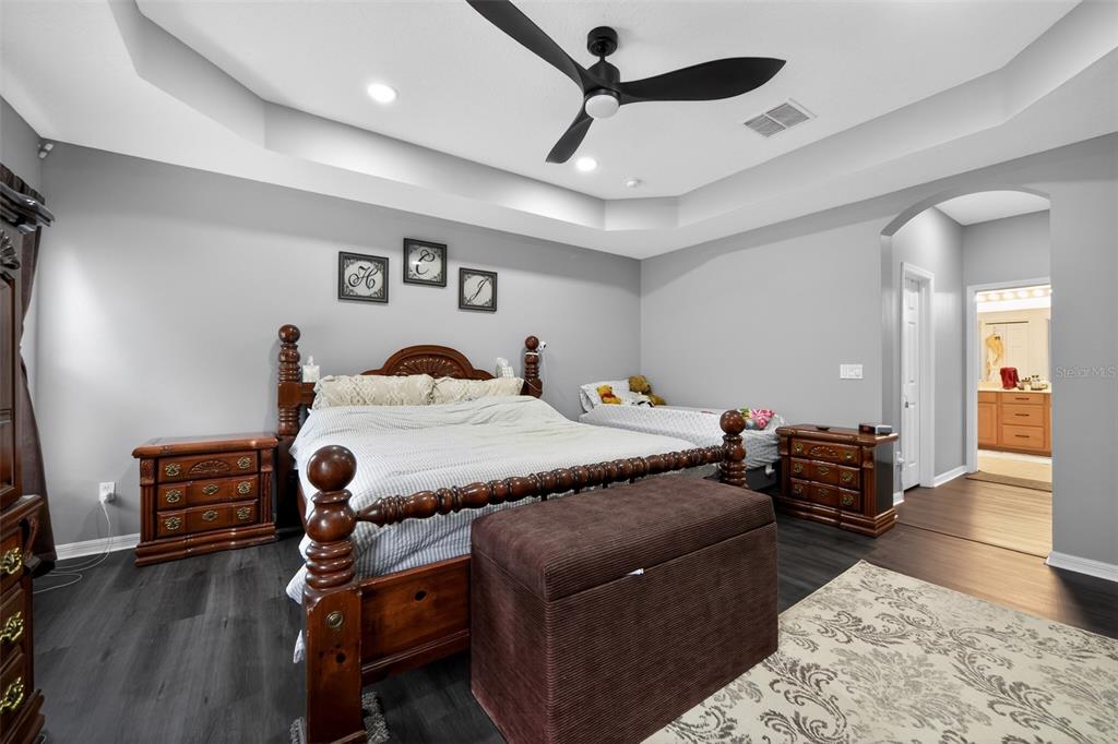 A bedroom features a wooden bed frame, a ceiling fan, and gray walls — 3651 DAYDREAM PLACE, ST CLOUD, FL