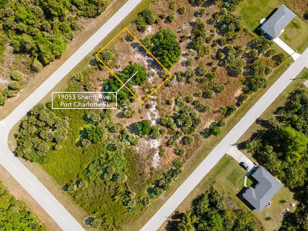 An aerial view shows a rectangular vacant lot outlined in yellow amidst undeveloped land — 19053 SHERIFF AVENUE, PORT CHARLOTTE, FL
