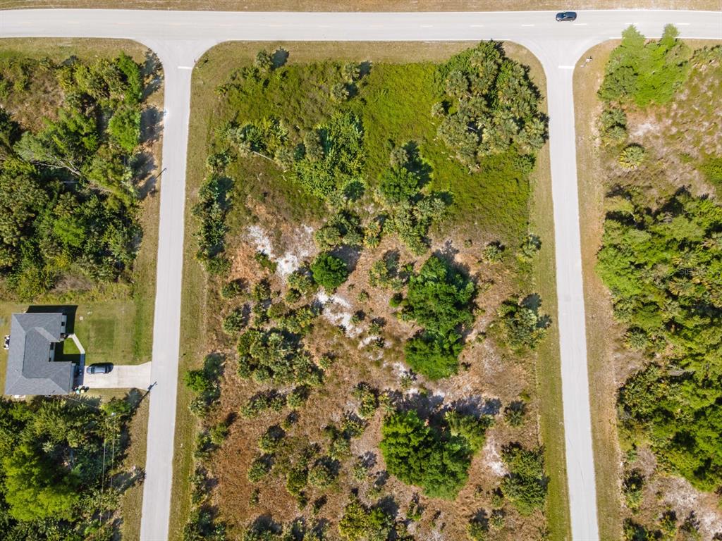 An aerial view shows a vacant, wooded corner lot bordered by two paved roads — 19053 SHERIFF AVENUE, PORT CHARLOTTE, FL