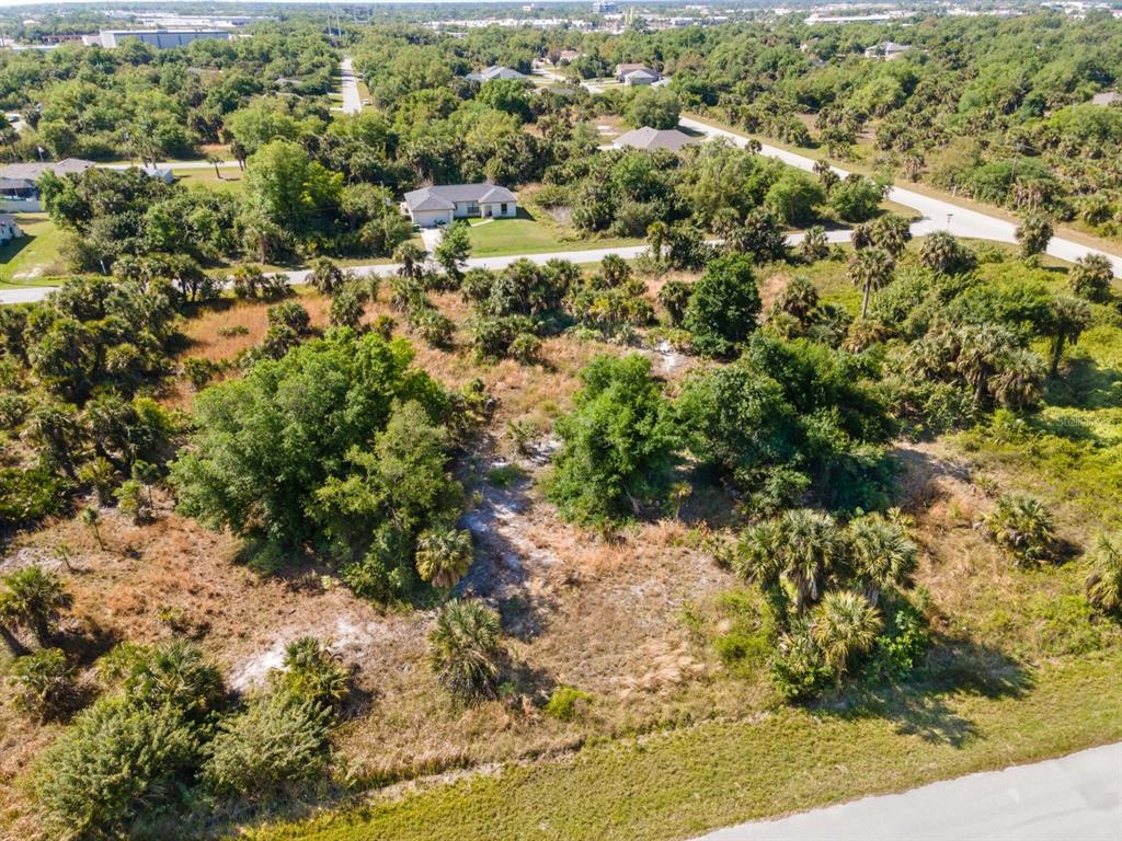 An aerial view shows a vacant, partially wooded lot bordered by paved roads and houses — 19053 SHERIFF AVENUE, PORT CHARLOTTE, FL